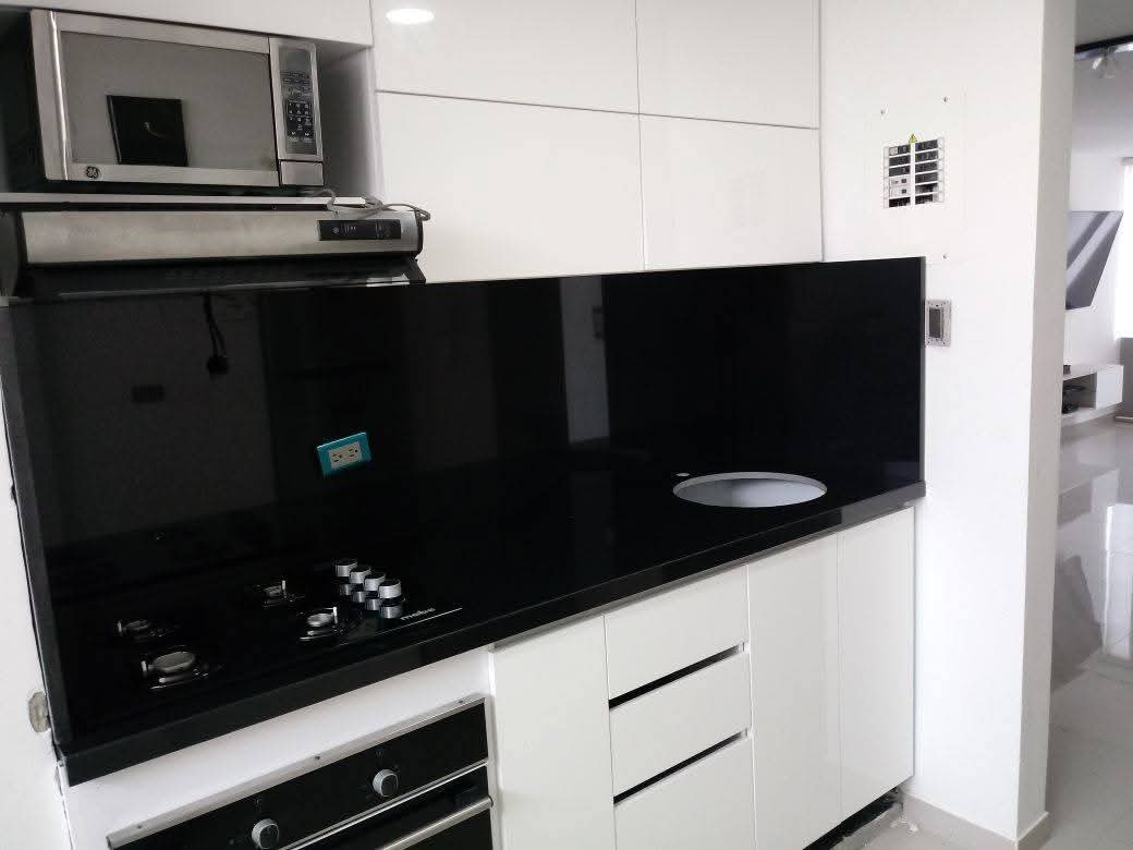 Cocina abierta al salón en un piso de Girona tras retirar el tabique, con viga integrada en el techo