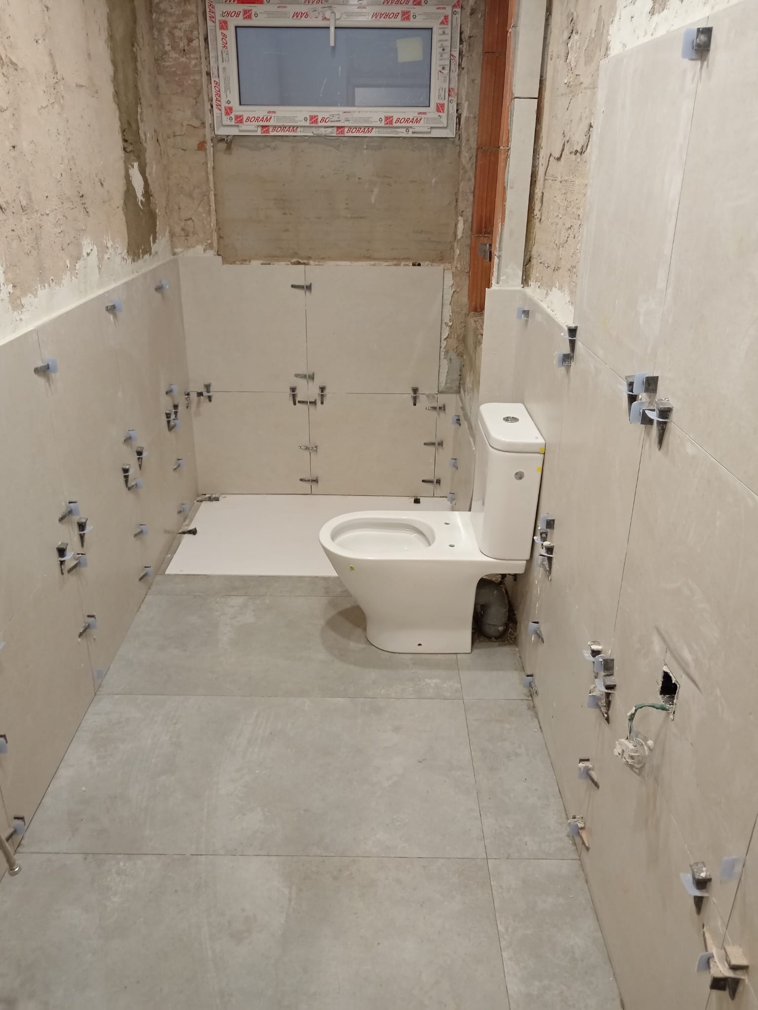 Zona de ducha de un baño en obra con membrana de impermeabilización aplicada antes del alicatado