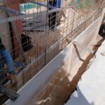 Operario montando encofrado y armadura de un muro de hormigón en obra